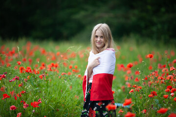 Blond girl wrapped in flag of Poland in the poppy field. Polish Flag Day. Travel and learn polish...