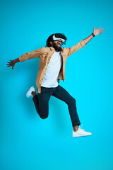 Full length of playful young African man wearing virtual reality glasses while hovering against...