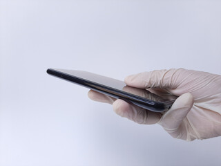 A hand with white latex glove holding a black mobile phone. Isolated on a white background