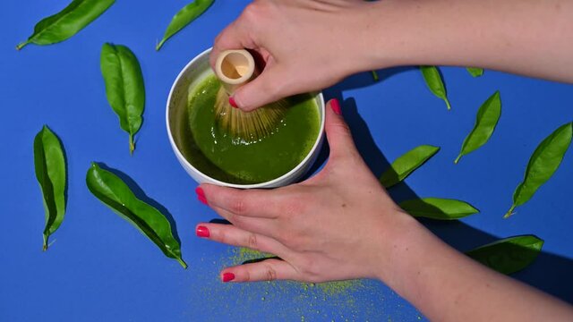 Matcha tea. A traditional oriental drink for health and energy. Powdered green tea and whisk. Photos are sharp in sharpness and hard light.  Woman is preparing a drink, process.