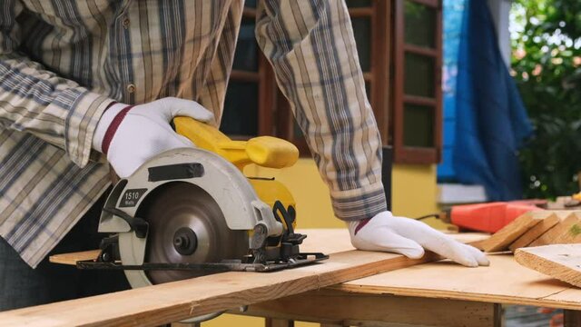 Slow motion,Close up of carpenter worker using saw cutting wood on construction site.