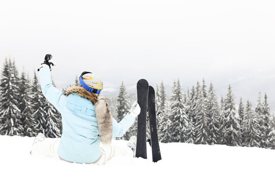 Woman Siting On Snow And Makes Selfie From Go Pro   With Ski Blades On Mountain In Forest In Winter Time