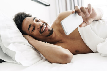 Photo of half-naked african american man using mobile phone and smiling