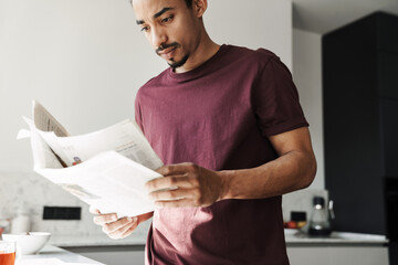 Photo of concentrated african american man reading newspaper