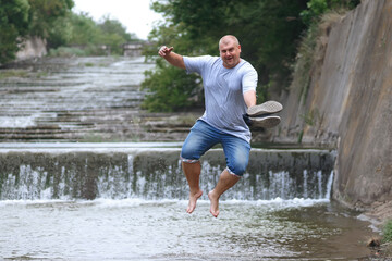big funny man jumping over the river