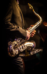 Saxophone in hands of a man in black suite