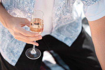 Seasonal feast at beach resort. Close up hands of man celebrating, resting, having fun. Holding glass with champagne. Festive time, wellness, holiday, party. Copyspace.