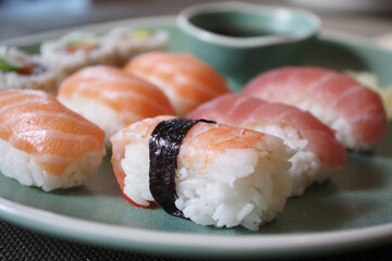 Japanese sushi food. Sushi set on green plate served with ginger and soy sauce. Sushi rolls, salmon nigiri, shrimp nigiri, tuna nigiri