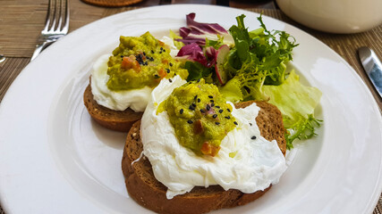 Two slices of dark bread with poached eggs on a white plate.