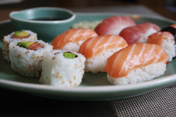 Japanese sushi food. Sushi set on green plate served with ginger and soy sauce. Sushi rolls, salmon nigiri, shrimp nigiri, tuna nigiri
