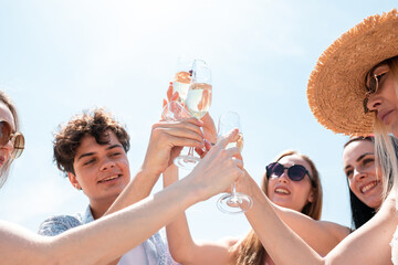 Close up clinking, cheers. Seasonal feast at beach resort. Group of friends celebrating, resting, having fun in sunny summer day. Look happy and cheerful. Festive time, wellness, holiday, party.