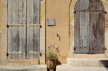 Closeup of a house in Provence, France, closed old wooden shutters and a door, a pot with lavender...