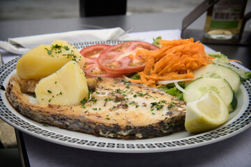 Traditional seafood dish from Madeira island cuisine is a variation of famous fish and chips - oily grilled swordfish fillet served with boiled potatoes and fresh vegetables