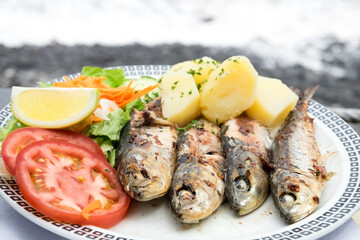 Traditional seafood dish from Madeira island cuisine - oily grilled sardines served with boiled potatoes and fresh vegetables