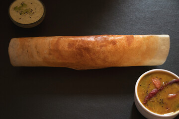 A dosa , originating from South India, made from a fermented rice and lentil served with sambar and coconut chutney