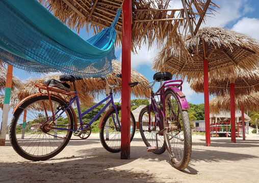 Two bicycles, one blue hammock and lots of straw beach umbrellas on the desert Pesqueiro beach, on Marajó Island, Brazil.