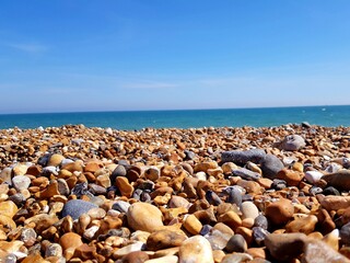 Fototapeta na wymiar Beautiful beach landscape with colorful stones and blue sky. Sea peblles beach. Beautiful nature.