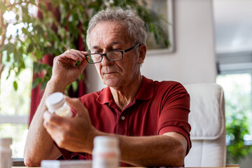 Senior man taking prescription medicine at home
 - obrazy, fototapety, plakaty