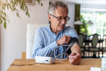 Senior man using medical device to measure blood pressure
