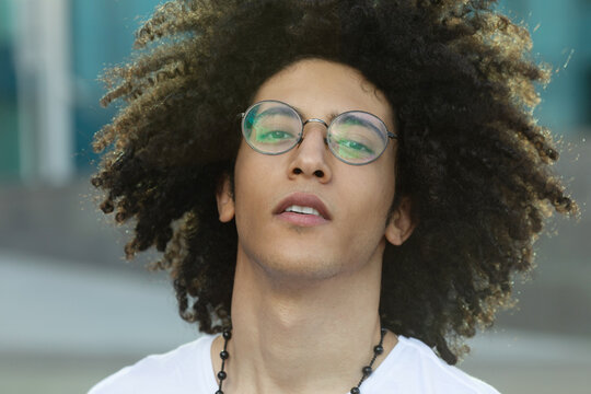 Close Up Portrait Of Handsome Young Black Man With Curly Hair Smiling Outside.