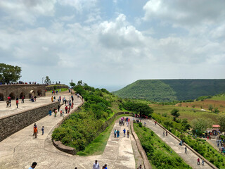 Mandav, Madhya Pradesh, India- July 14, 2019: Spiral concrete road for enter in Rani Rupmati Mahal/Pavilion at Mandu. People are coming to visit this heritage place. A flat top hill in the background.