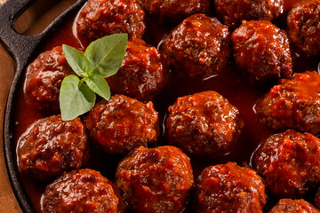 Traditional spicy meatballs in tomato sauce on wooden background. Selective focus.