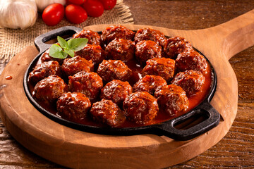 Traditional spicy meatballs in tomato sauce on wooden background. Selective focus.
