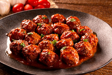 Traditional spicy meatballs in tomato sauce on wooden background. Selective focus.
