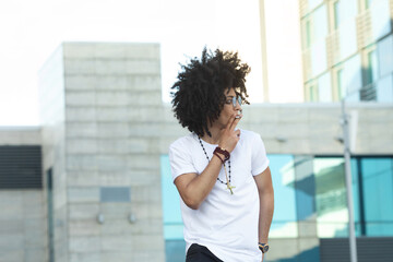 Fototapeta na wymiar Young black man with curly hair smoking outdoors.