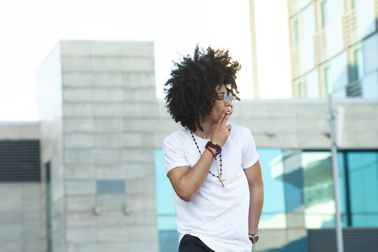 Young black man with curly hair smoking outdoors.
