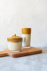 Dalgona coffee on a light gray concrete background.