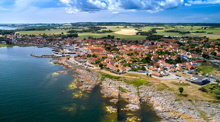 Panorama der dänischen Stadt Svaneke auf der Insel Bornholm an einem Sommertag mit Blick auf die Granitfelsen und Häuser mit roten Dächern. - obrazy, fototapety, plakaty