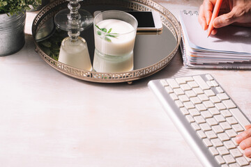 Hands working from home, taking notes and typing, with a dessert in a tray