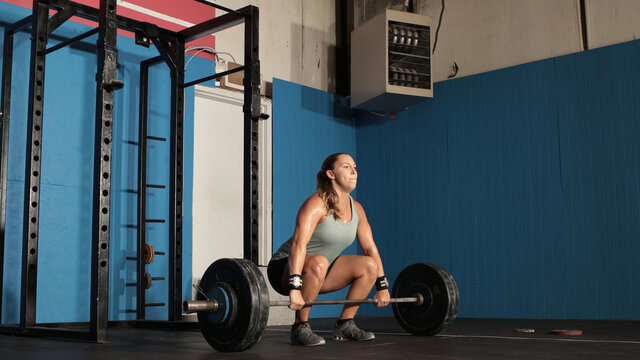 Young Strong Woman Lifting Heavy Weights In Grungy Gym.