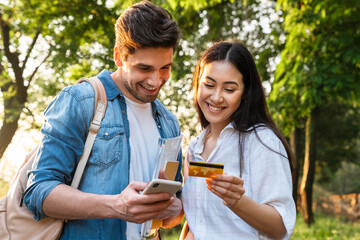 Image of student couple using mobile phone and holding credit card