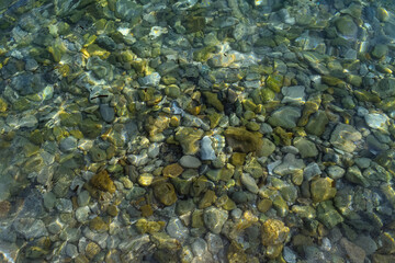 Obraz na płótnie Canvas Colored stones in clear water of sea with sunny bunnies