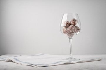 Date sweets with coconut shavings in a wine glass near the copy space on a white napkin