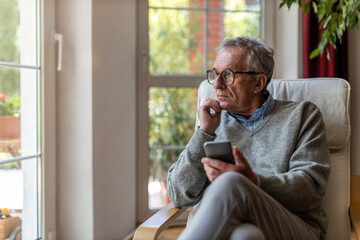 Senior man using mobile phone at home
