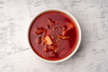 Vegetarian borscht in a white tureen on a light wooden table top view