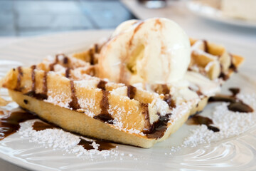 Traditional Belgian homemade waffles with sweet chocolate sauce and a cup of vanilla ice cream served at the confectionery of Funchal, Madeira island