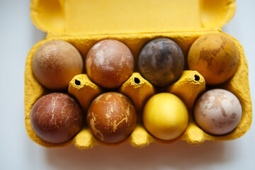 yellow box with eight original, unique colorful dragon or dinosaur looking like chicken Easter eggs, dyed with natural products (red wine, tea, coffee, carrots, turmeric, soy sauce)