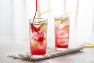 Two glasses of ice cold lemonade with lemon. Pour the syrup into the glass.
