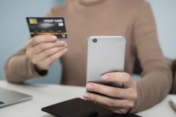 young woman hand using digital mobile phone scan and payment online with credit card on desk in home office, electronic payment, money cost saving, online shopping, business finance, expenses concept