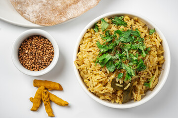 Kichari in a white plate on a light table near condiments and tortillas top view