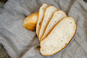 Slices of bread lie on a wooden table. Wheat flour is scattered, a knife for cutting bread.