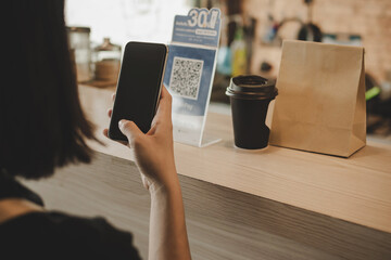 woman customer using digital mobile phone scan QR code pay for buying coffee in modern cafe coffee shop, cafe restaurant, digital payment, online shopping, takeaway food, internet technology concept