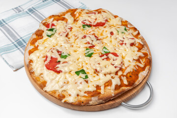 Vegetarian pizza on a wooden round Board on a white table near the kitchen napkin