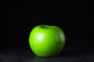 Green apple on a black background. One green apple in the frame