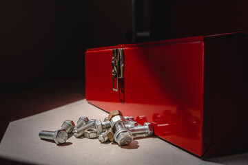 open red tool box on concrete, inside nuts and bolts. lock. light and shadow from the window. close up