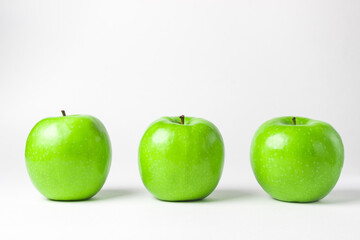Green apples on a white background. Three green apples stand in a row